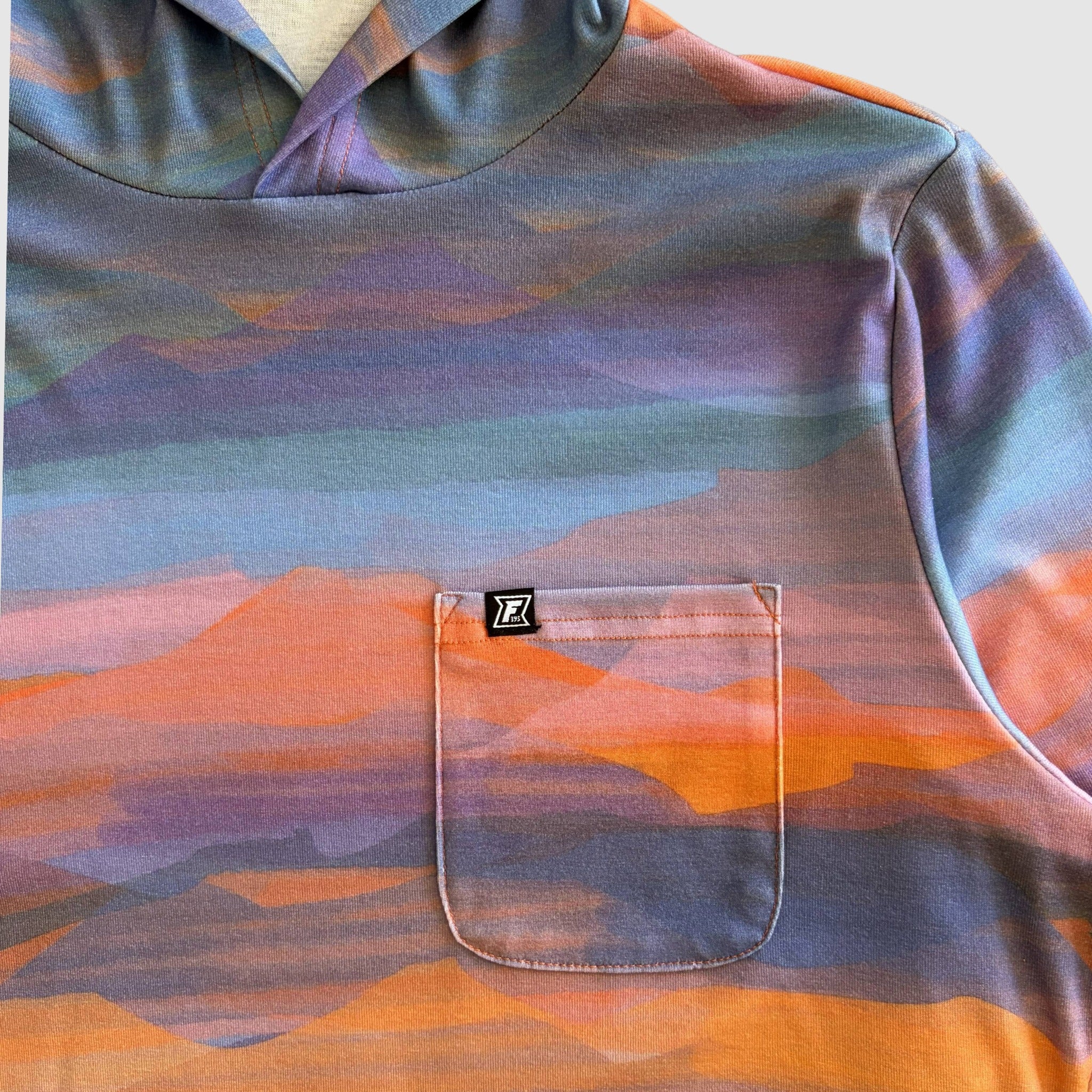 Multicolored hooded shirt with a pocket and FaultLine395 brand logo on a neutral background
