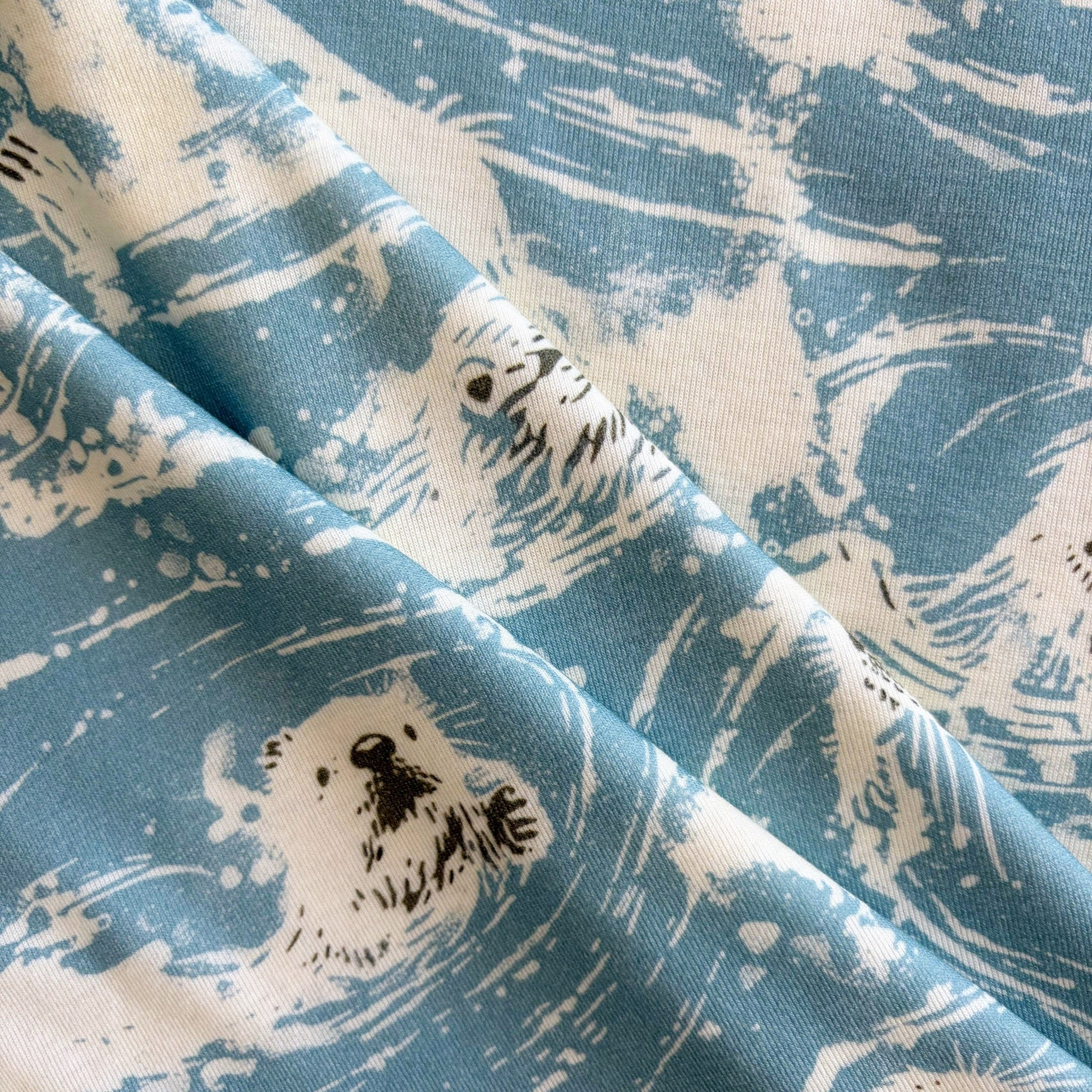 Closeup of the fabric used on the Women's Carson sun hoodie with white otter pattern on a blue background