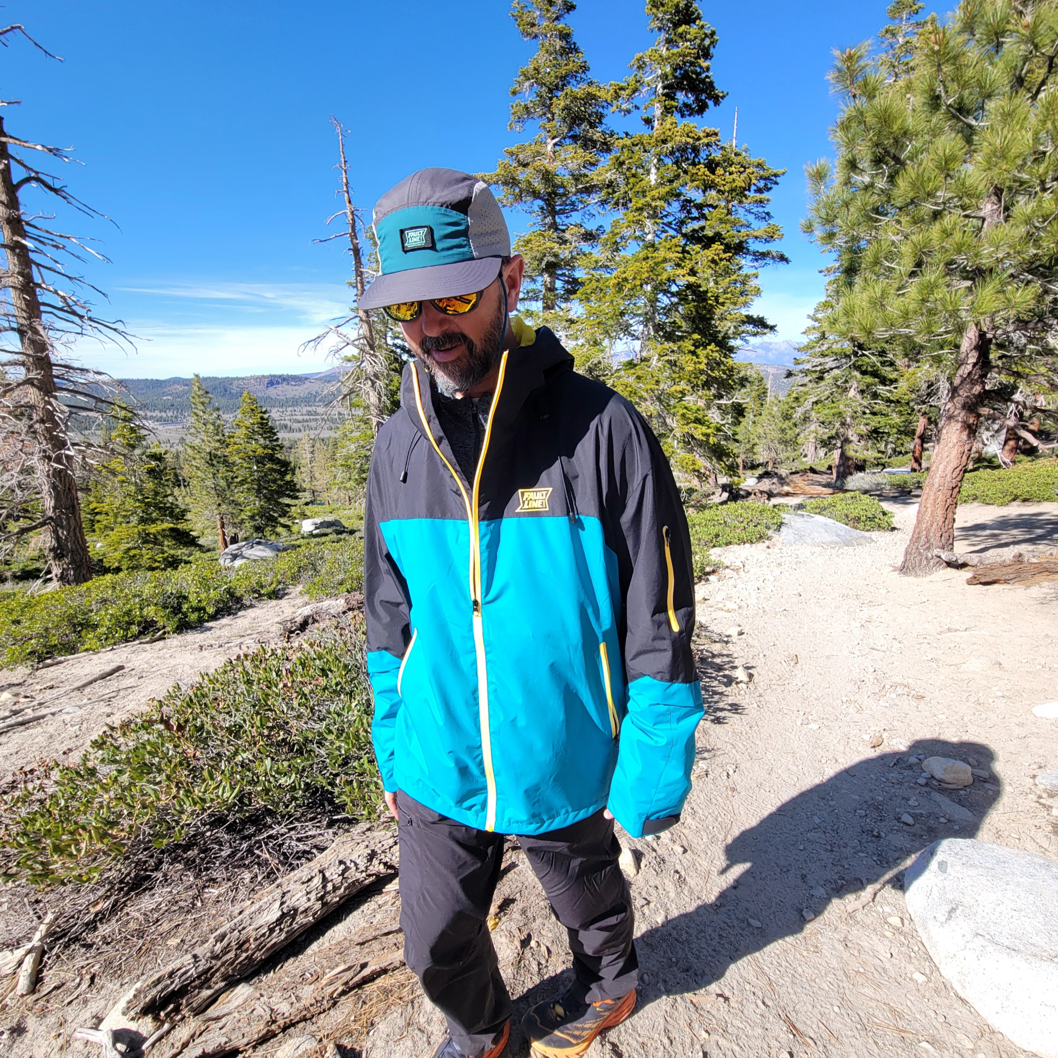 Hiker wearing the Forest Trail Jacket in Black and Teal on a hiking trail, demonstrating its comfort and versatility.