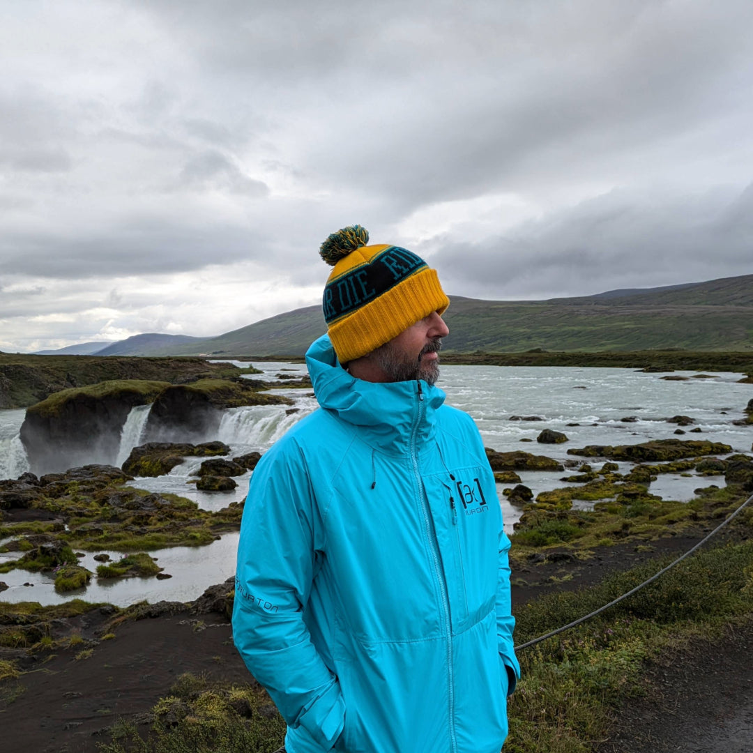 Person wearing the Ride or Die Beanie in front of a waterfall in Iceland.