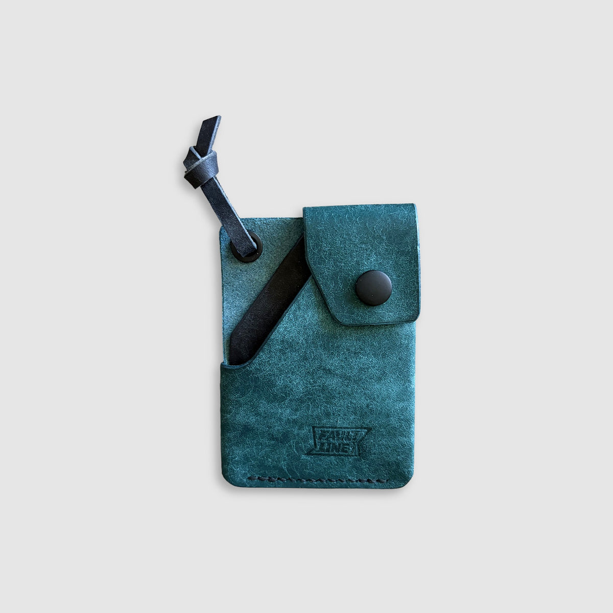 A teal blue-green leather card holder wallet with a black leather strap and button closure, featuring a debossed 'FaultLine395' logo, shown on a light gray background.