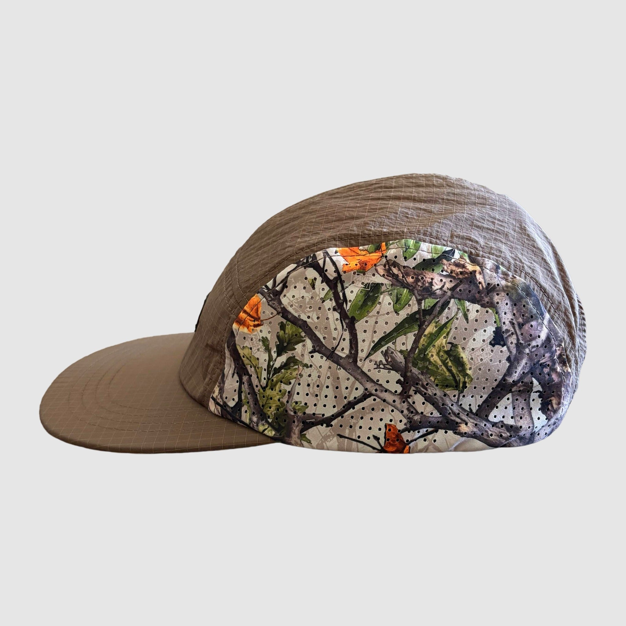 Camouflage-patterned cap with brown brim on a light gray background