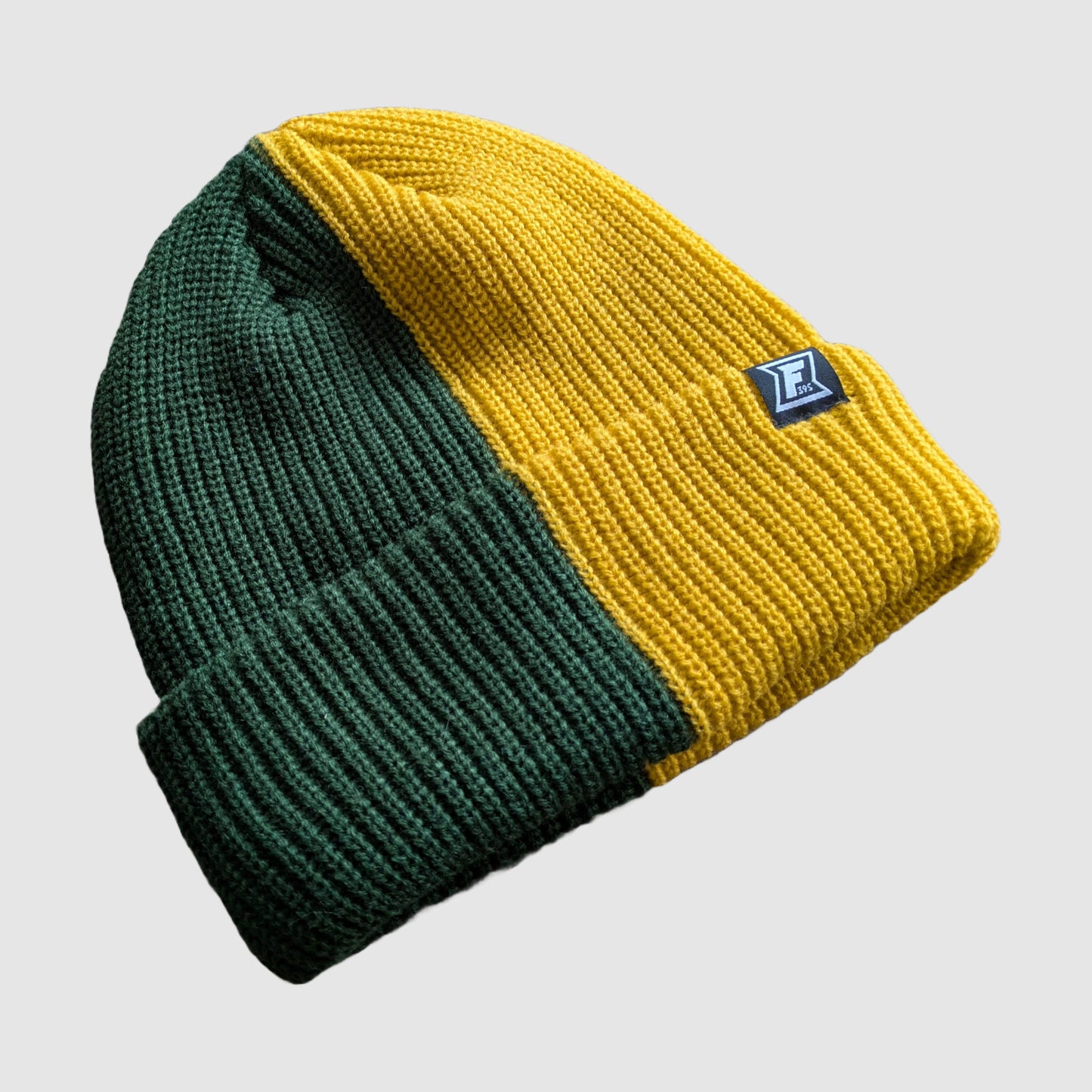 Detailed view of a Faultline395 beanie that is half yellow and half green.