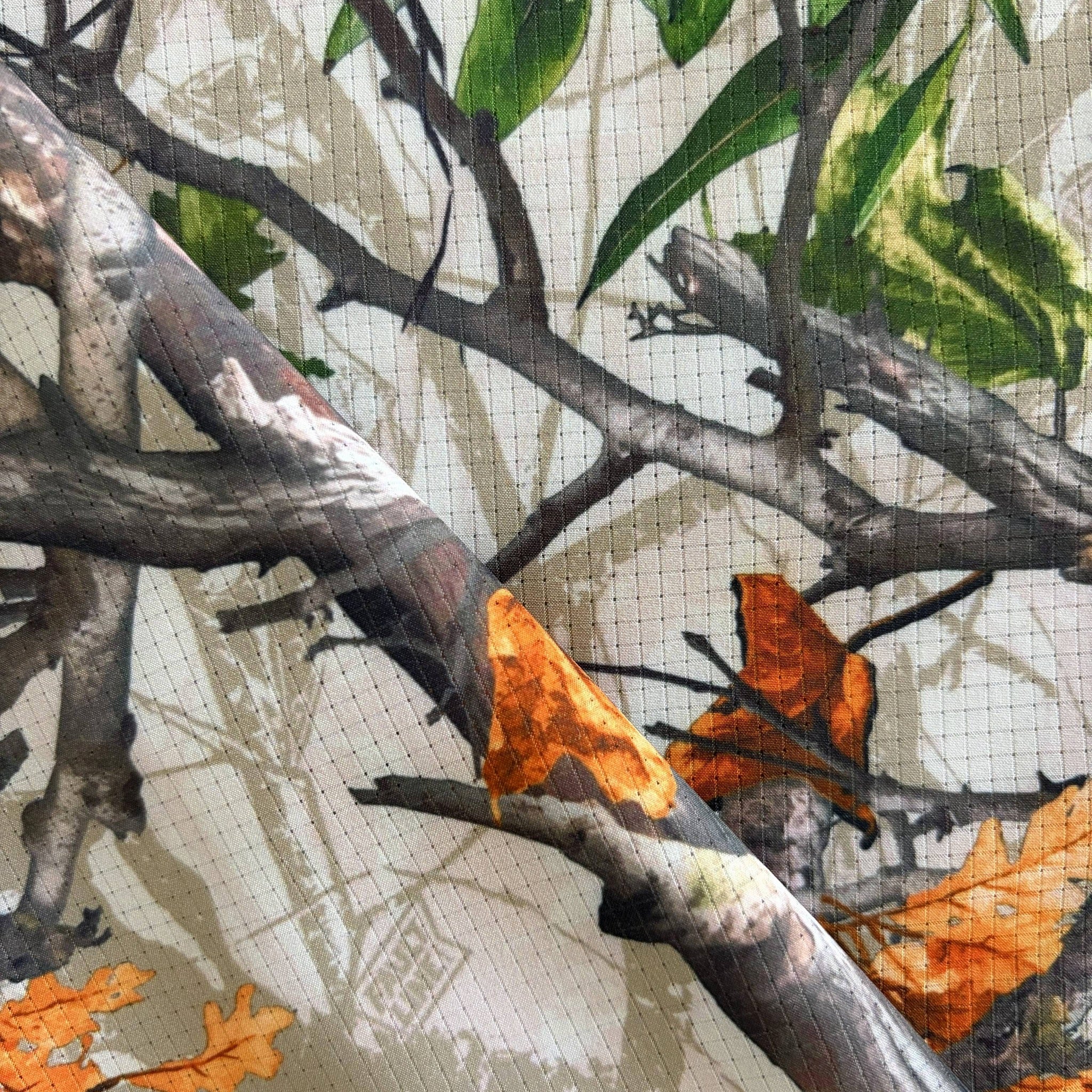 Close-up of a fabric with a nature-themed pattern featuring leaves and branches.