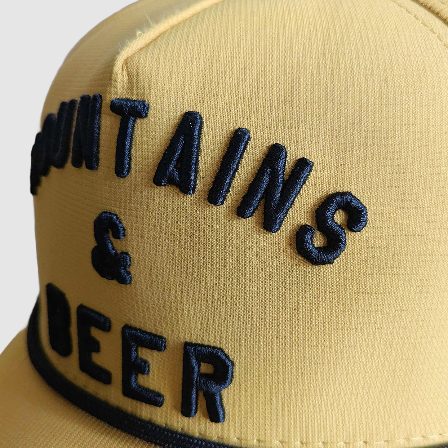 Close up of the 3D raised embroidery on the Mountains & Beer snap back hat.