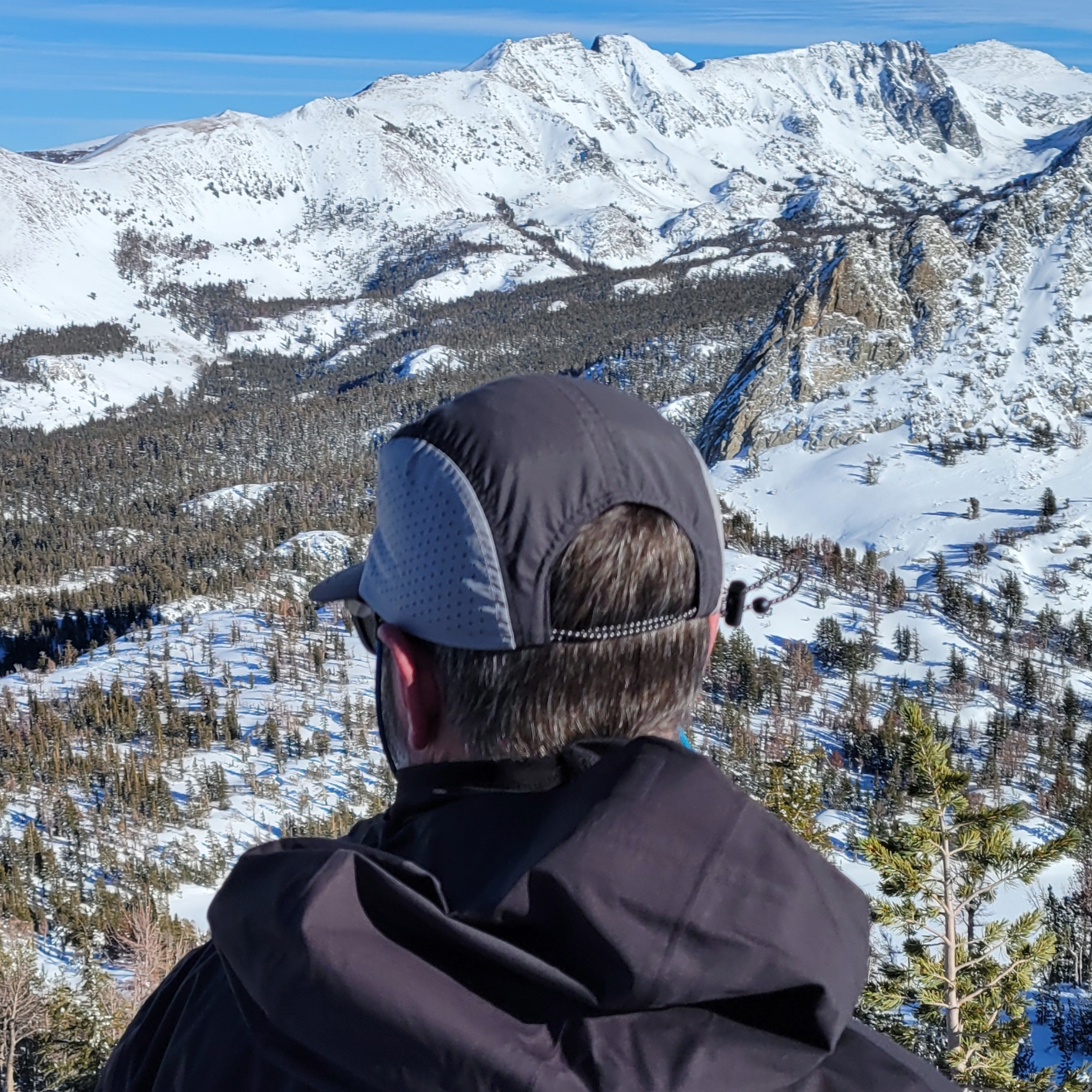 Back view of a person wearing the Faultline395 5-Panel hat in the mountains showing the cinch cord closure