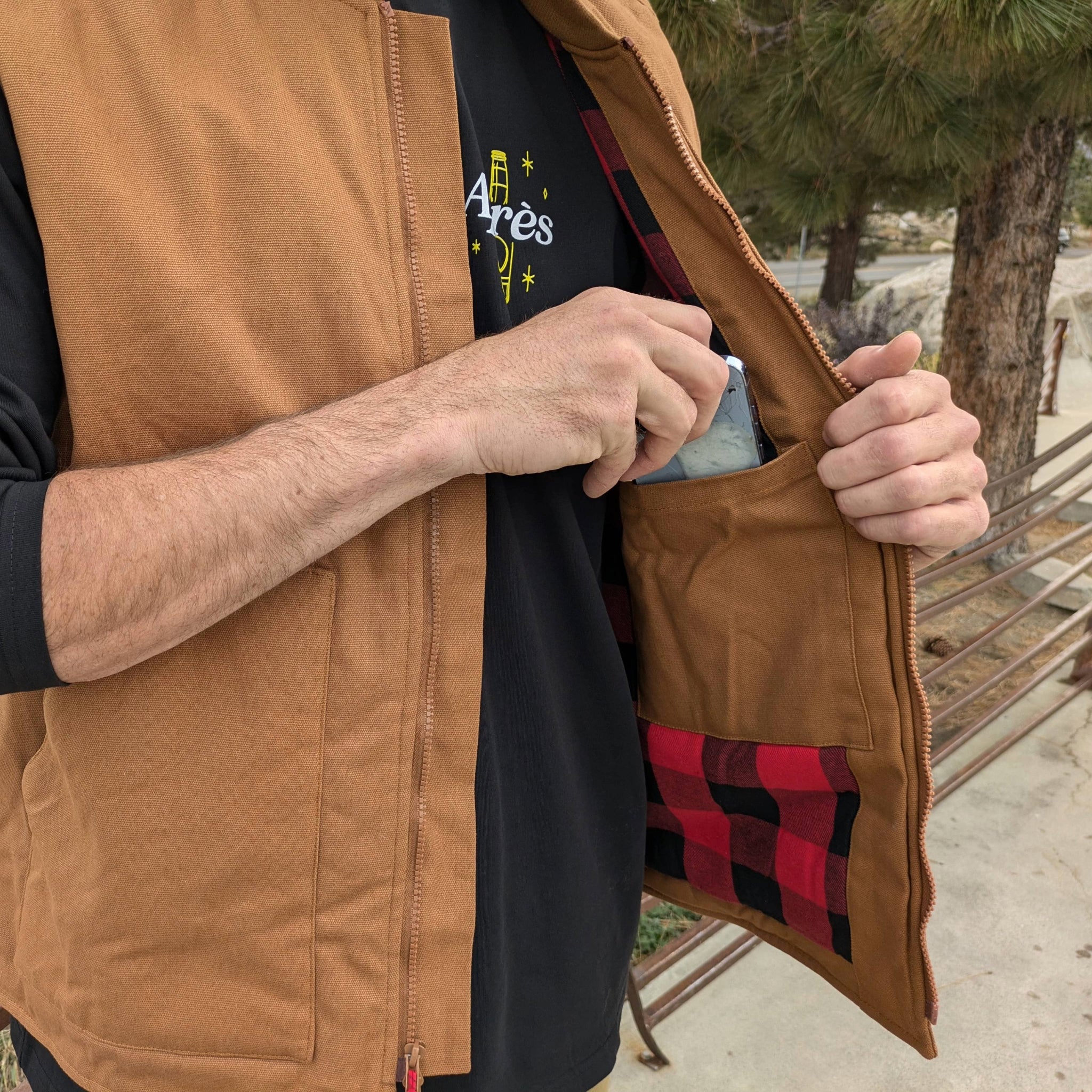 Close up of a person making use of the cell phone pocket on the Faultline395 work vest.