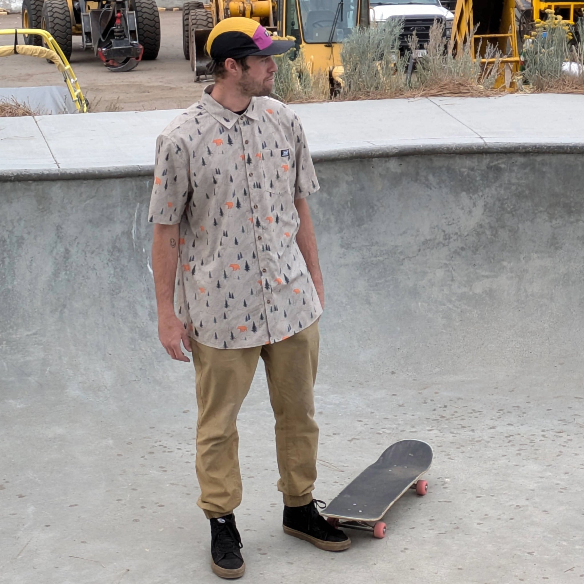 Skateboarder wearing the Faultline395 button up shirt in khaki with a bear print design