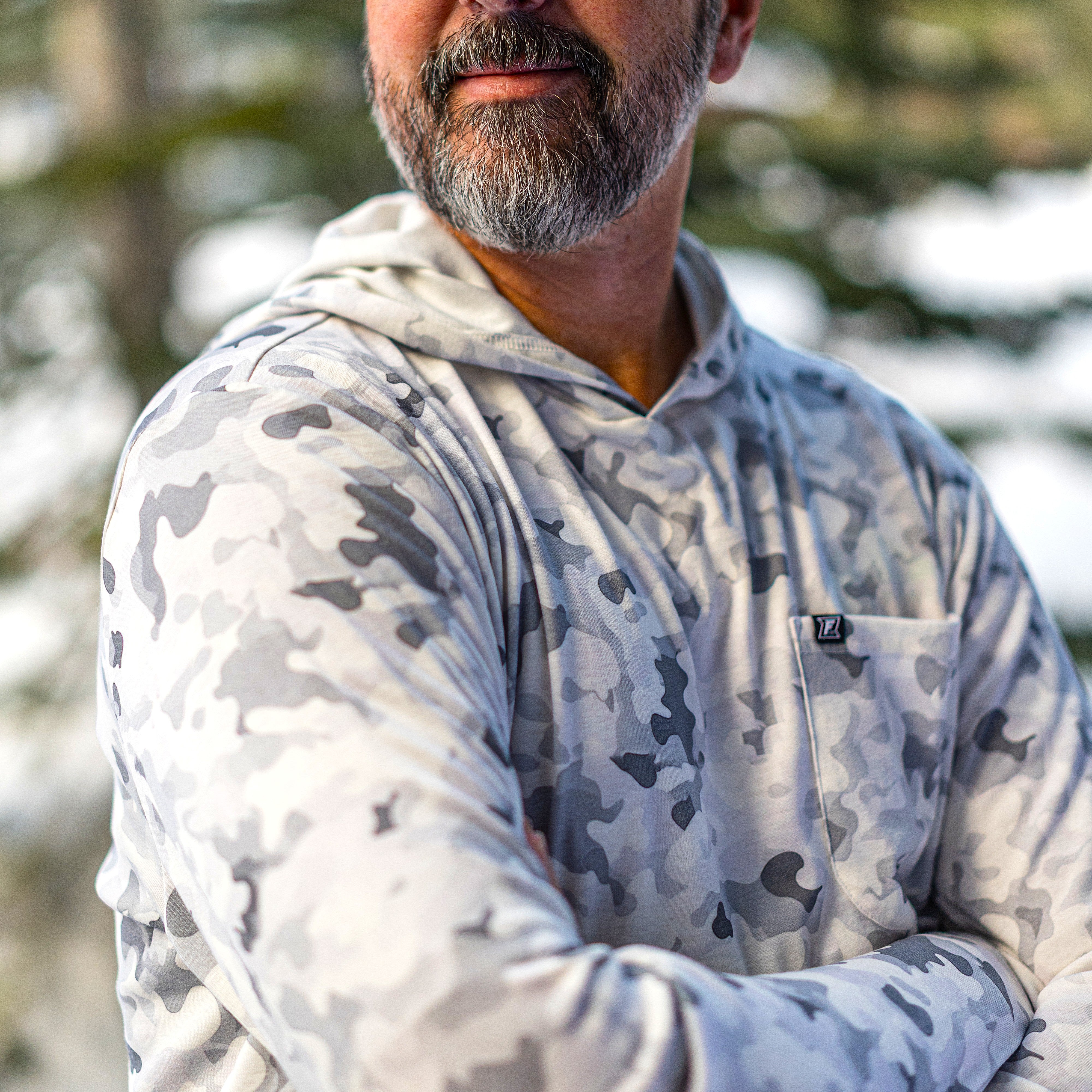 Man wearing a camouflage hoodie with a blurred natural background